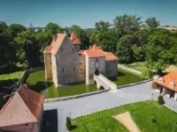 Château médiéval entouré de douves et verdure.