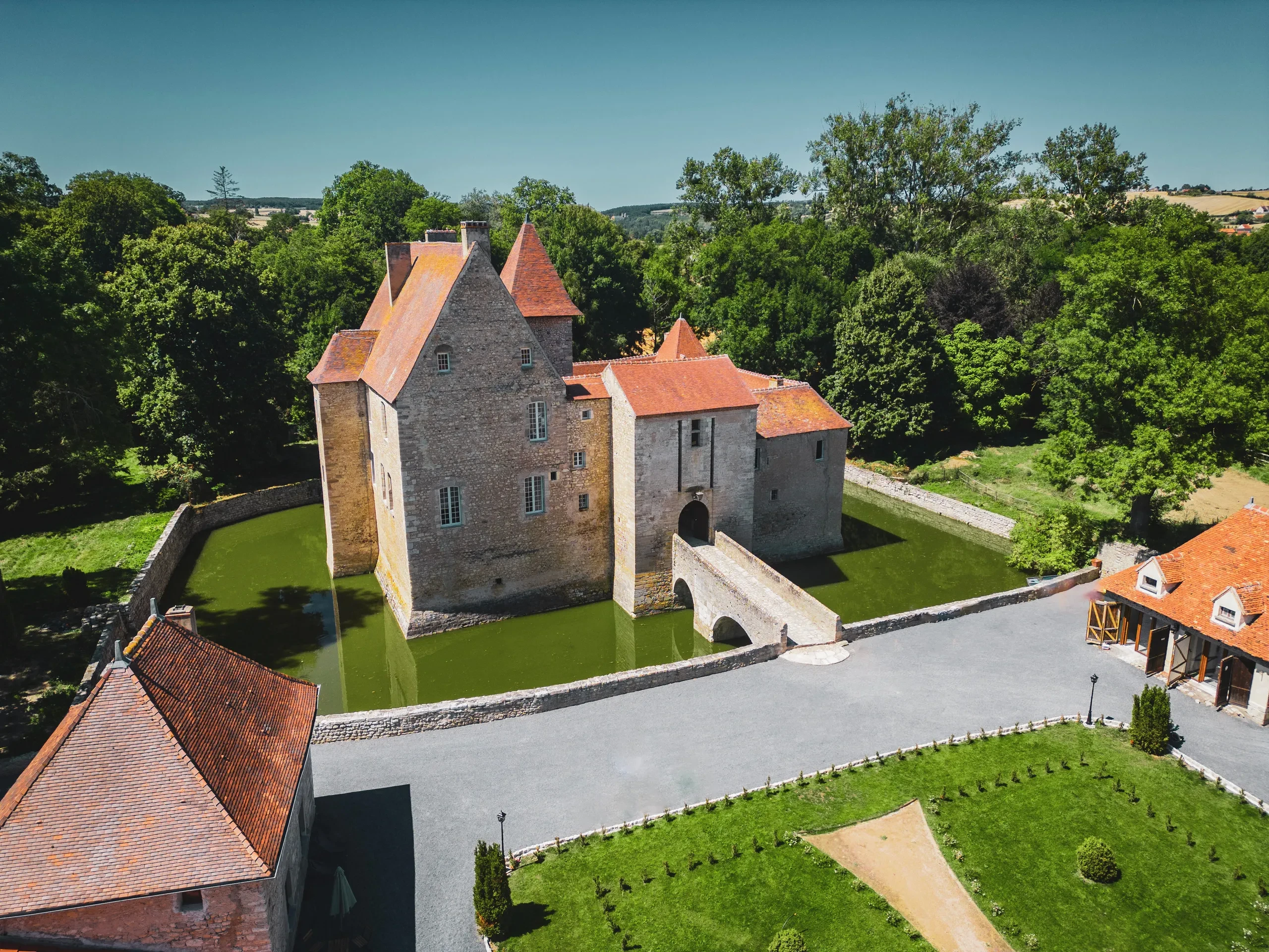 Château médiéval entouré de douves et verdure.