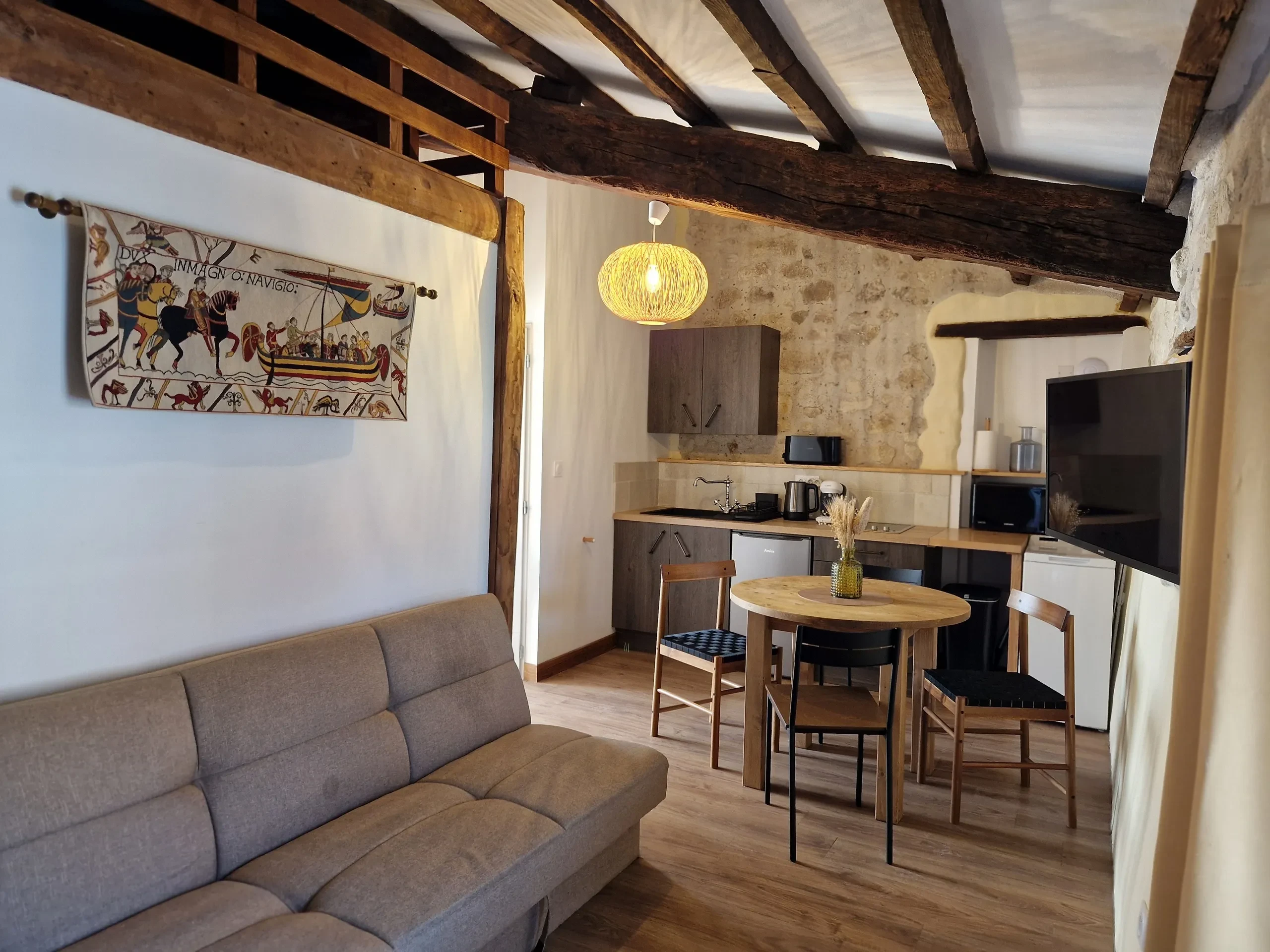 Salon rustique avec cuisine ouverte et décoration médiévale.