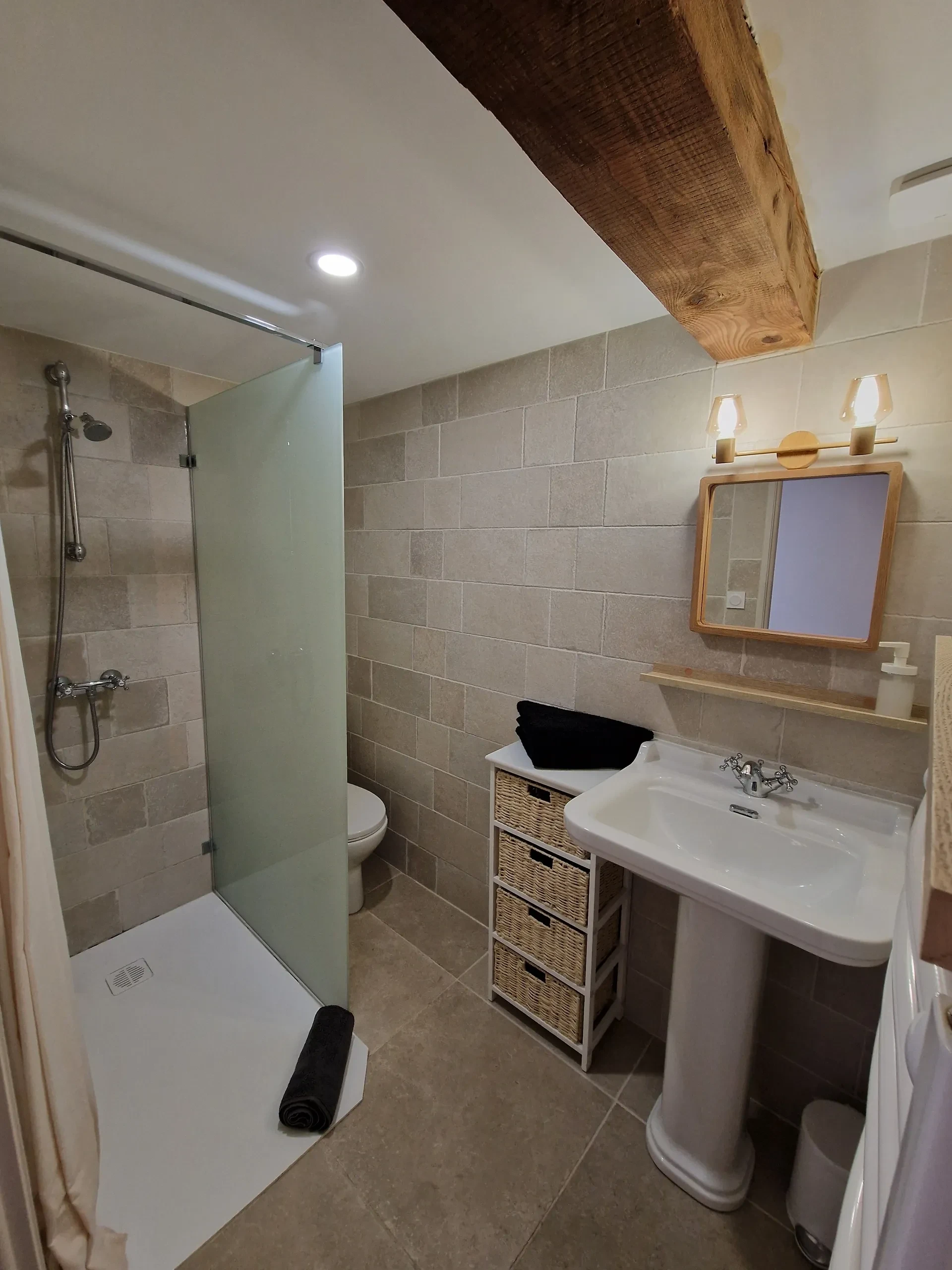Salle de bain moderne avec douche et lavabo.