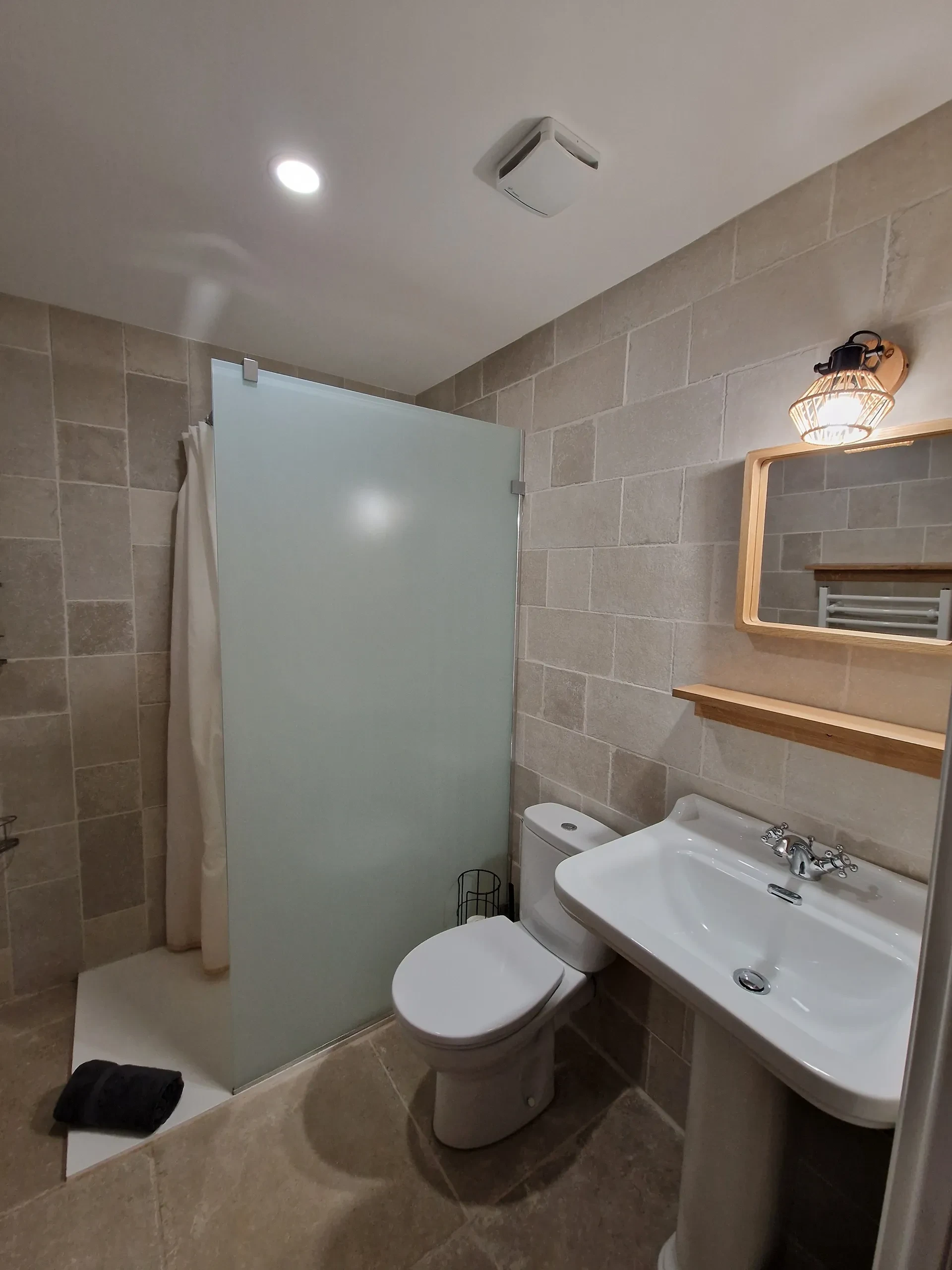 Salle de bain moderne avec douche, toilette et lavabo.