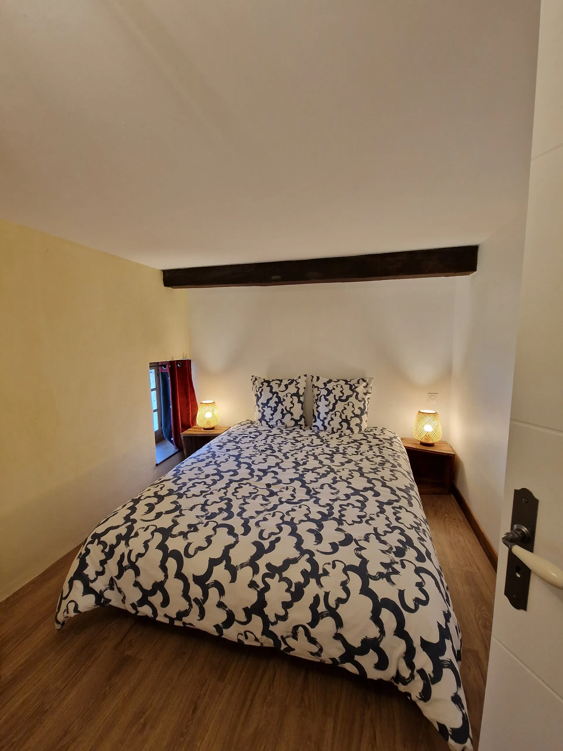 Petite chambre avec lit double et lampes.