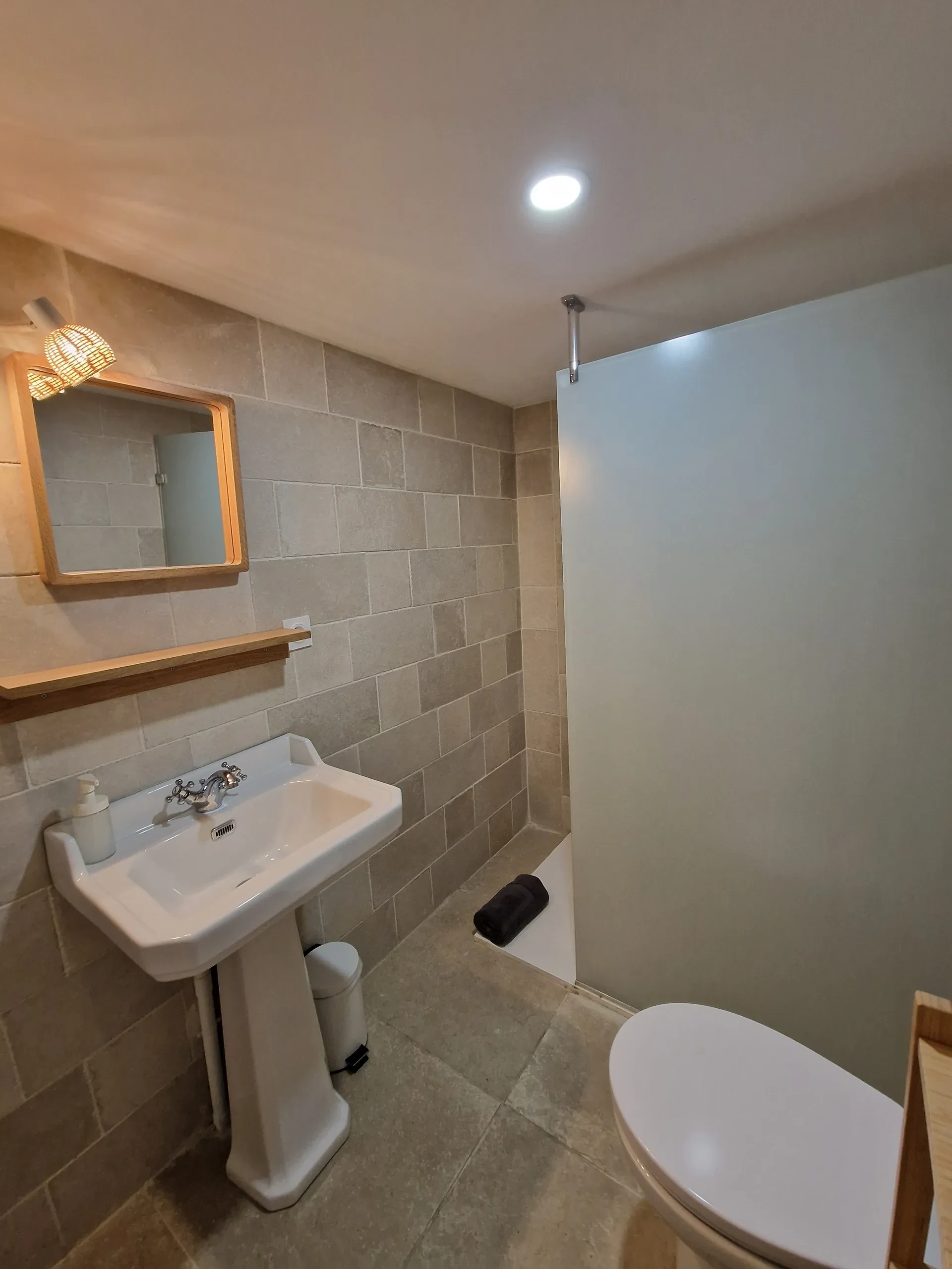 Salle de bain moderne en carrelage avec lavabo et douche.
