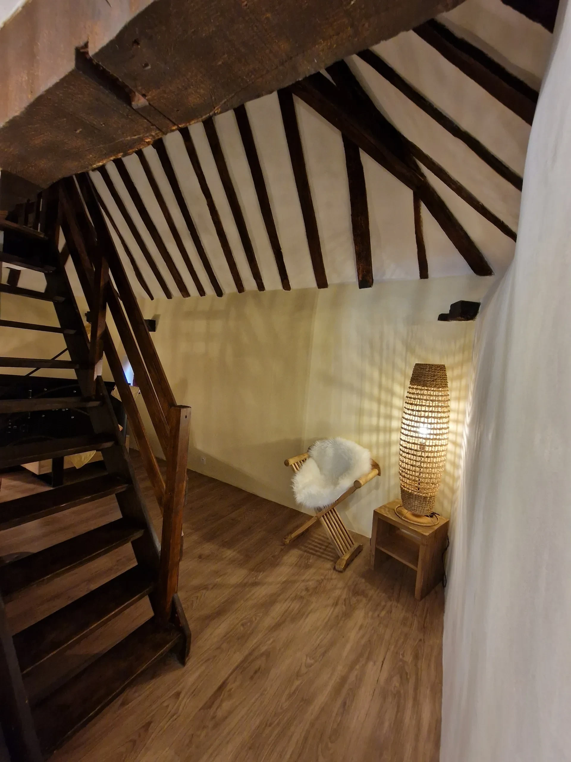 Coin détente sous escalier avec lampe et fauteuil.