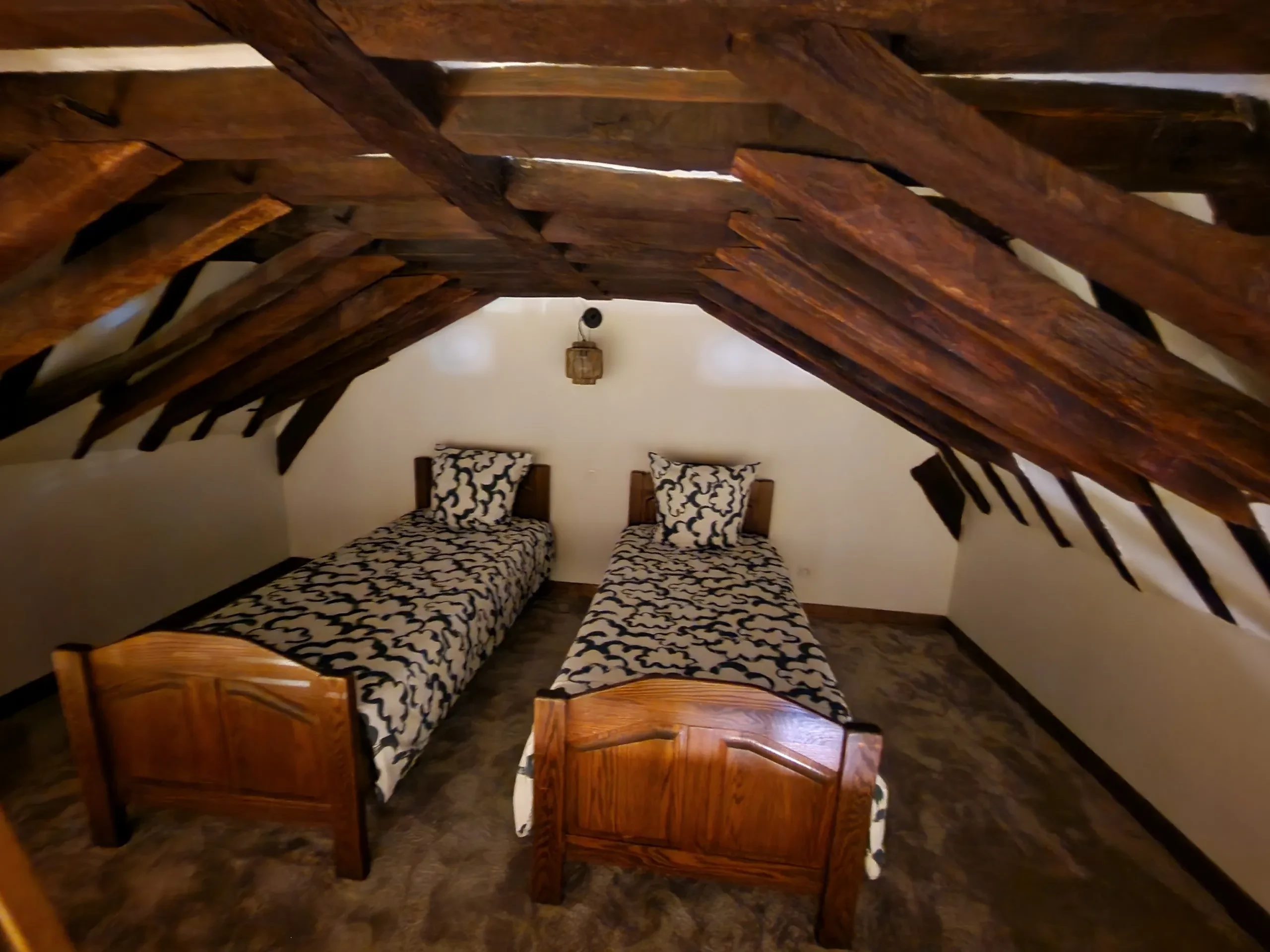 Chambre mansardée avec deux lits simples en bois.