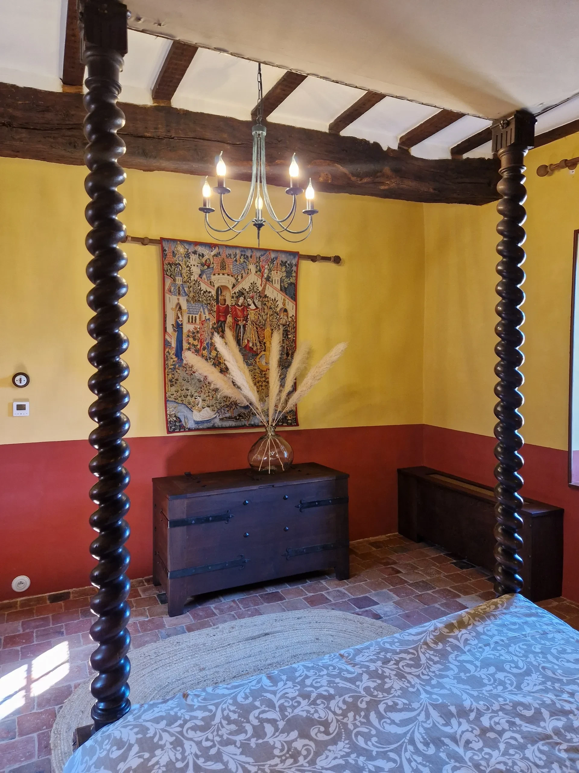 Chambre rustique avec lit à baldaquin et tapisserie colorée.