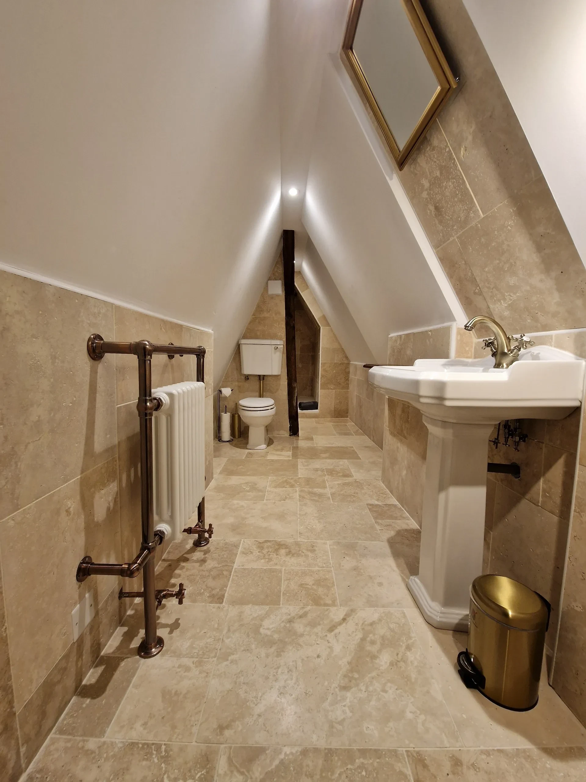 Salle de bain mansardée avec lavabo et toilettes.
