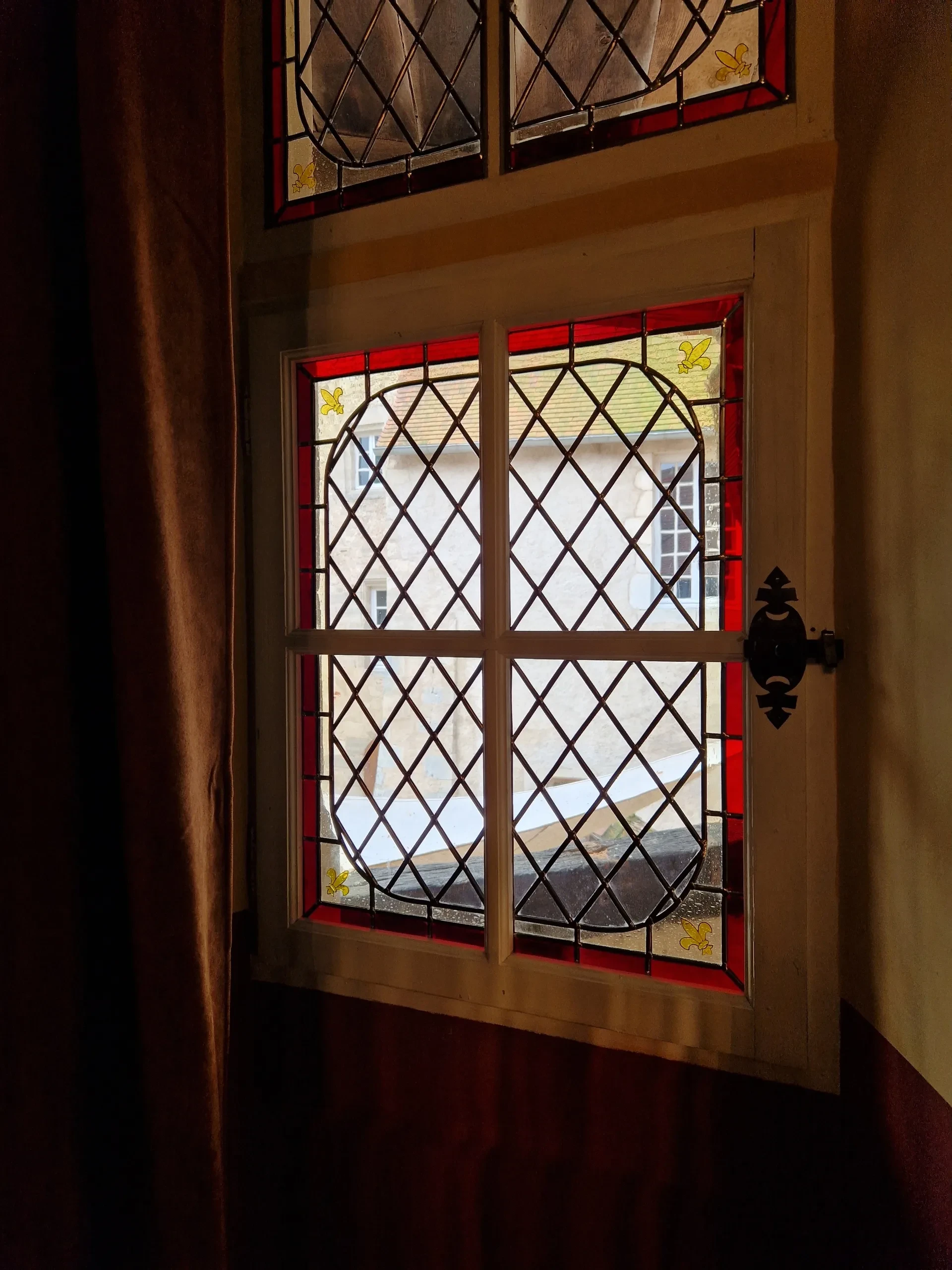 Vitrail coloré avec motifs géométriques et nuances rouges.