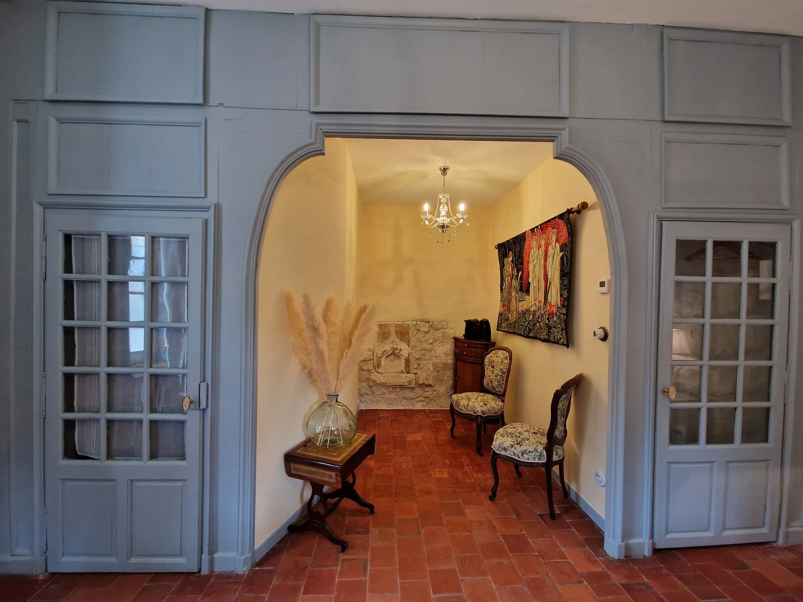 Entrée avec chaises et tapisserie décorative.