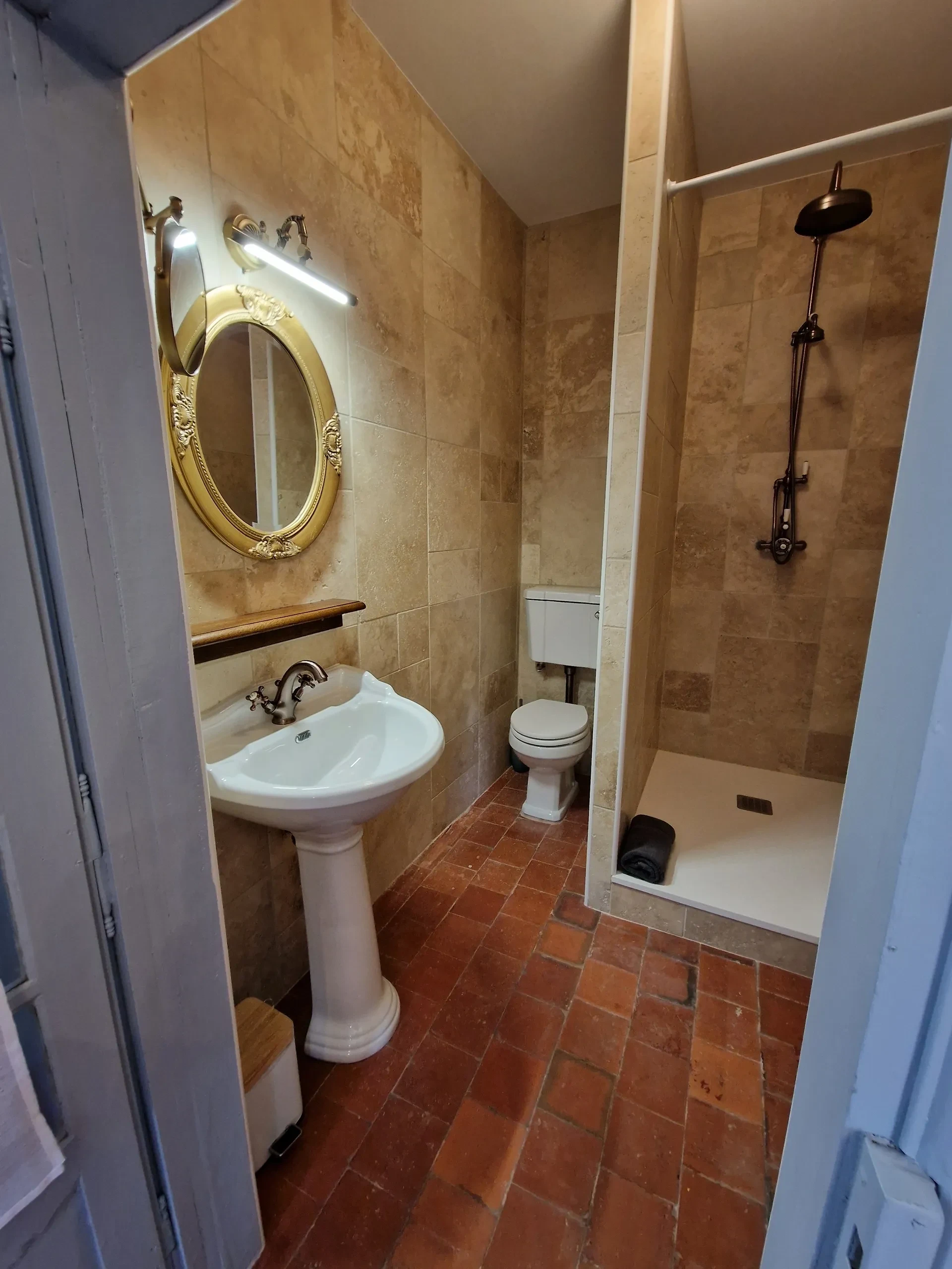 Salle de bain avec douche et lavabo.