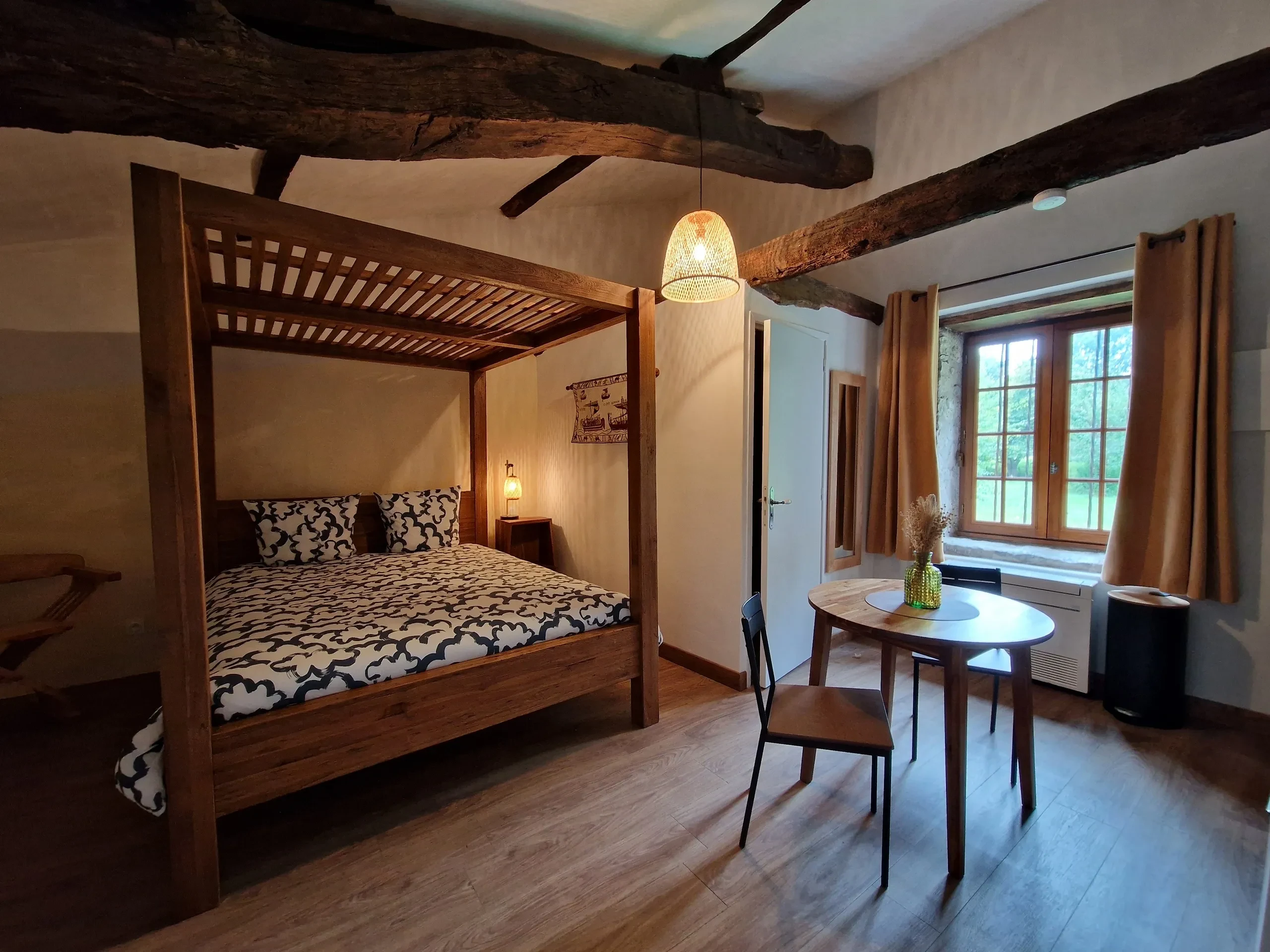 Chambre rustique avec lit à baldaquin et table.
