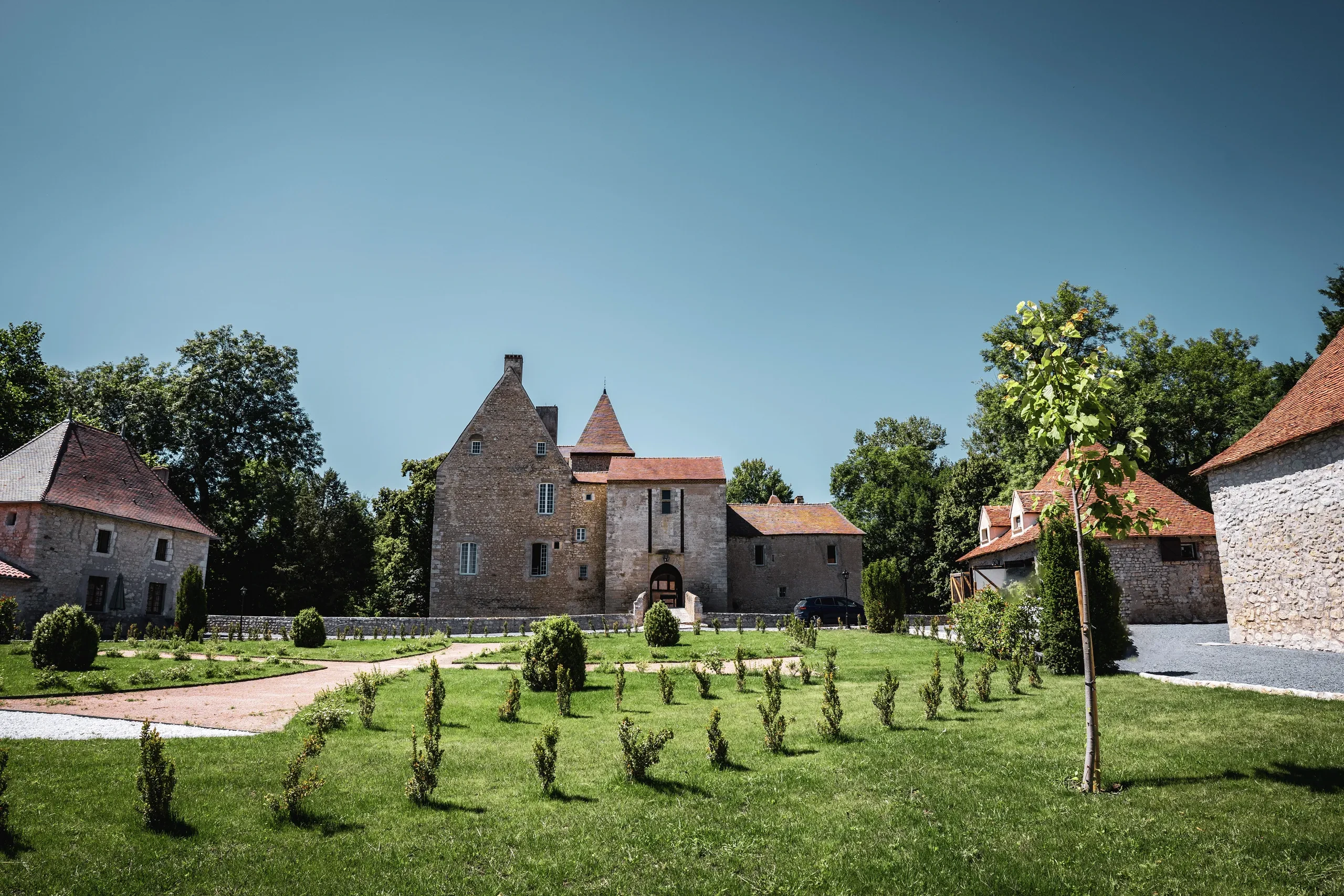 Jardin verdoyant devant un château en pierre.