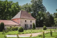 Maison en pierre dans un jardin verdoyant.