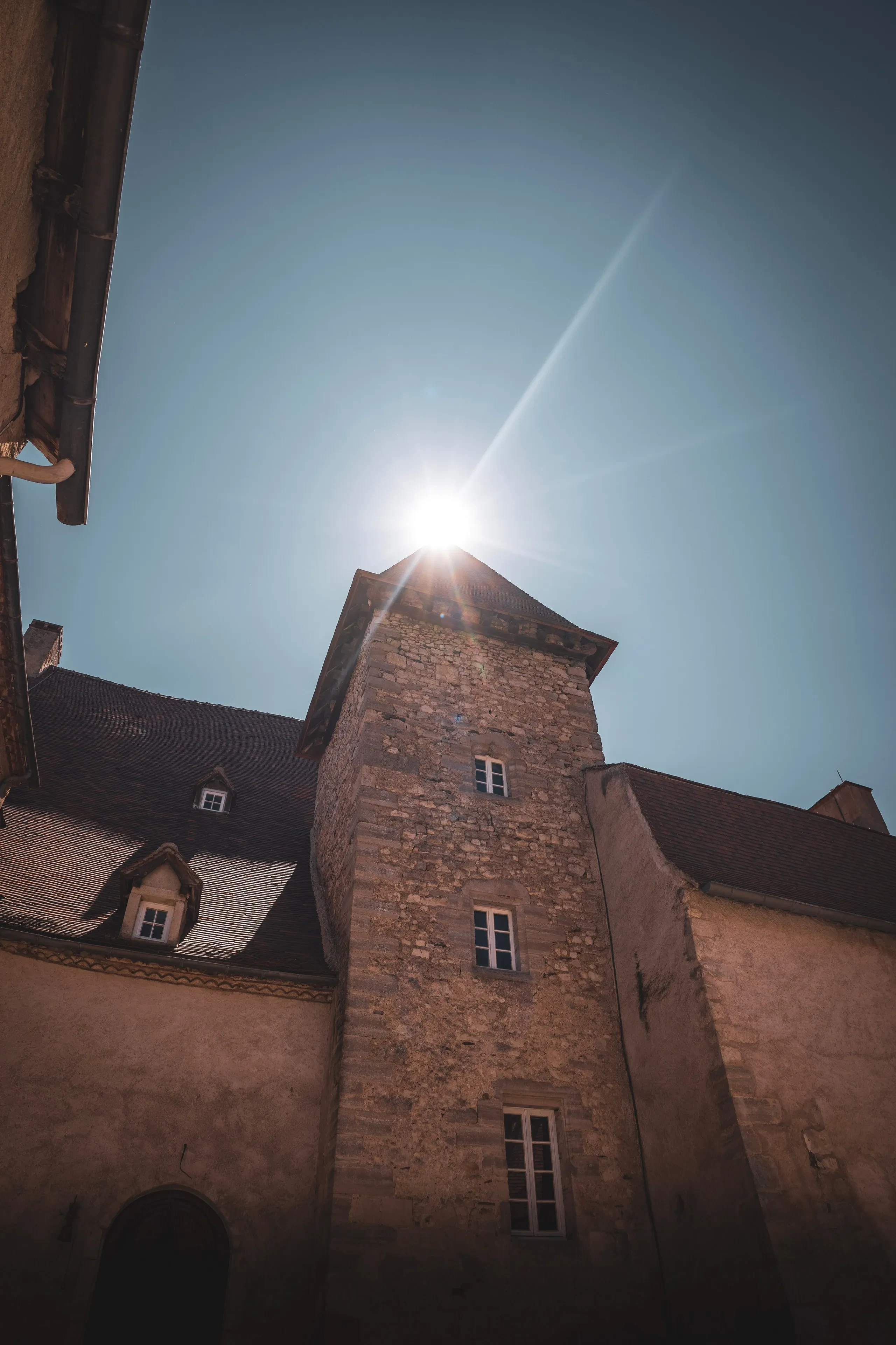 Vieux bâtiment en pierre sous soleil éblouissant.