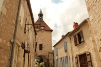 Rue avec tour et horloge dans village français.