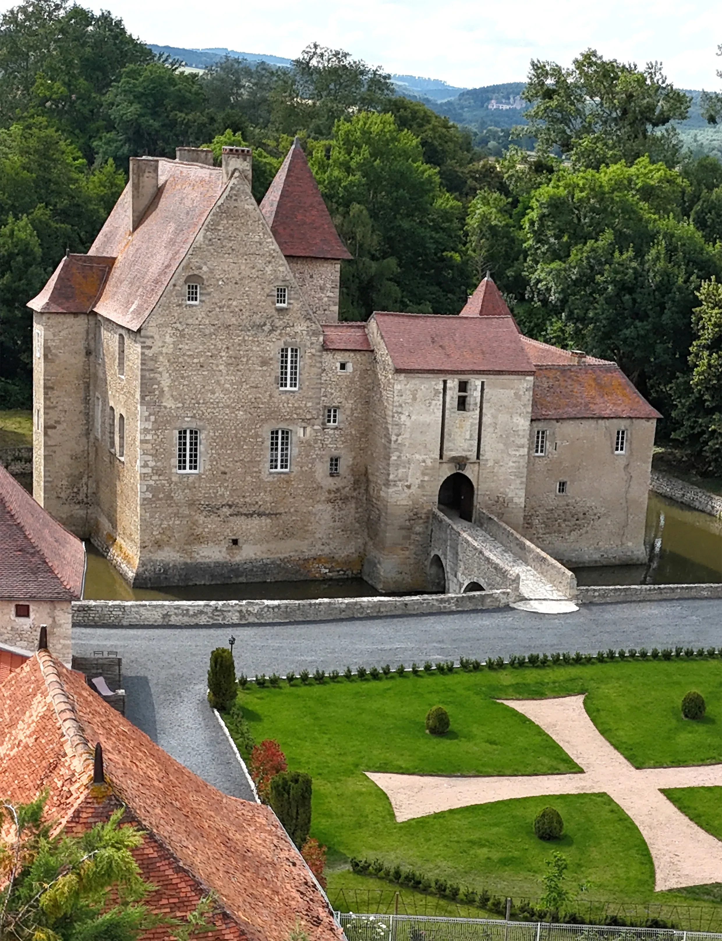 Château médiéval entouré de verdure et douves.