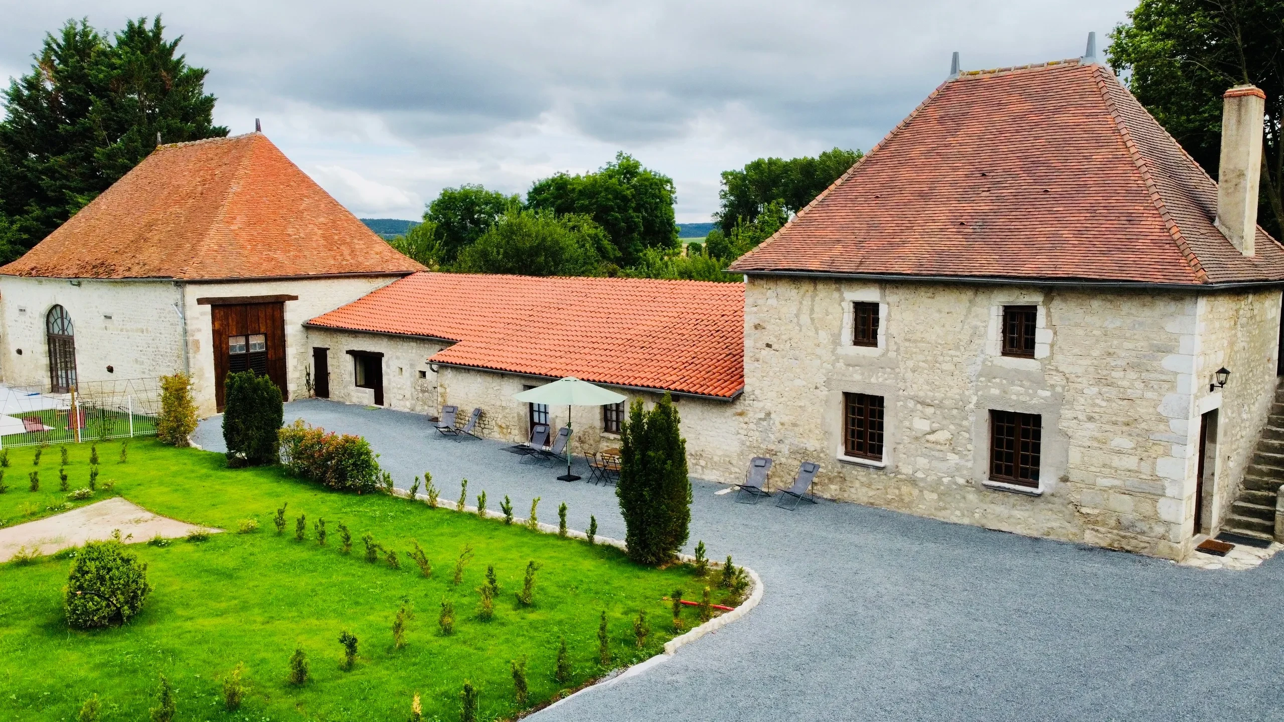 Cour et bâtiments en pierres avec toit rouge.