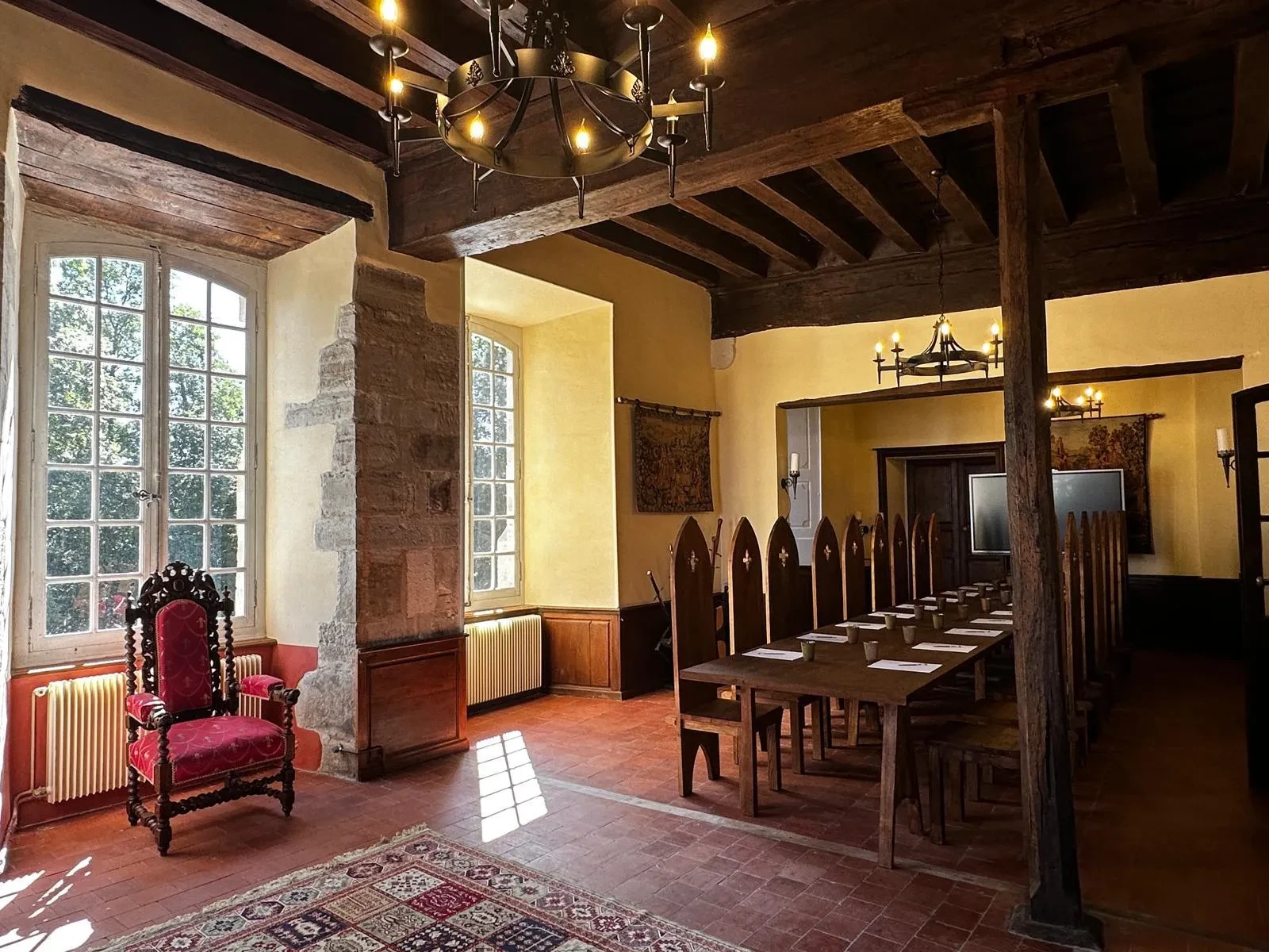 Salle médiévale avec fauteuil et grande table.
