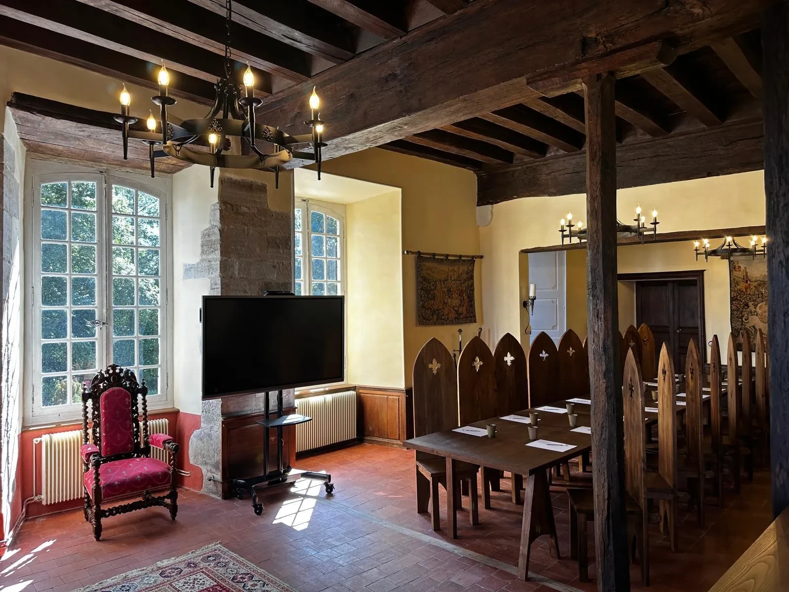 Salle médiévale avec cheminée et chaises anciennes.