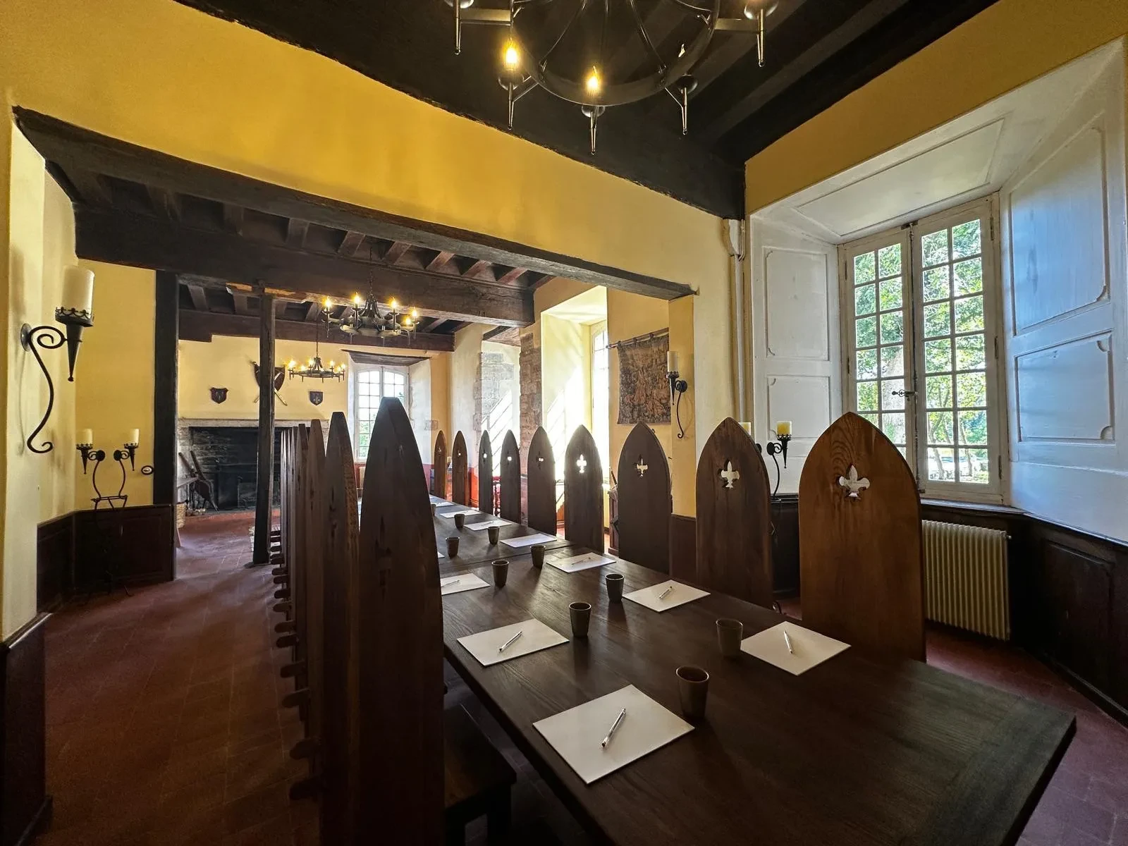 Salle à manger médiévale avec grandes chaises en bois.