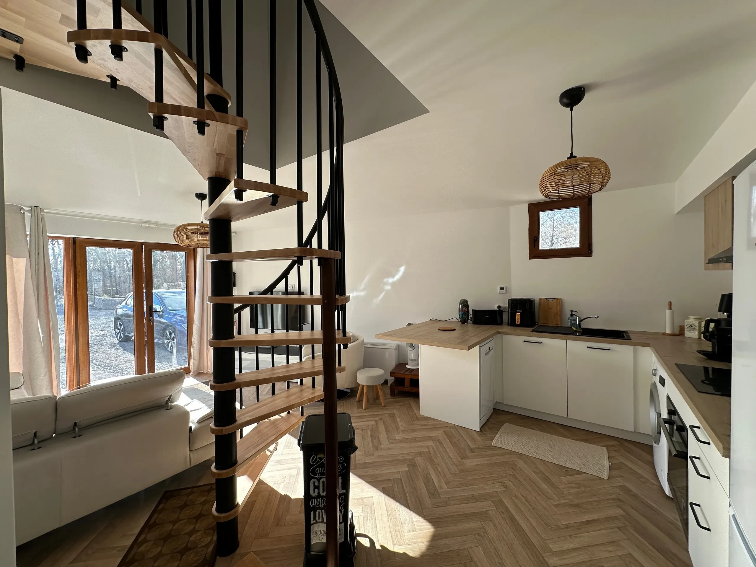 Intérieur moderne avec escalier en colimaçon et cuisine équipée.
