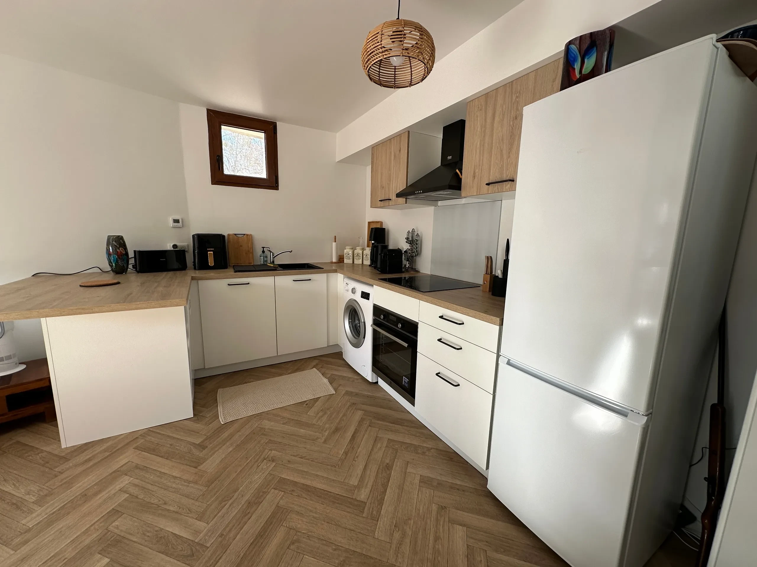 Cuisine moderne avec électroménager et parquet en bois.