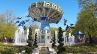 Manège carrousel avec jets d'eau et buissons taillés.