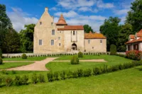 Château ancien avec jardin et ciel bleu.